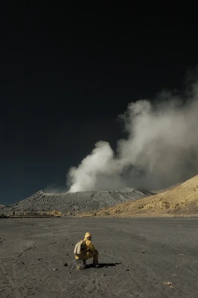 Turista sedersi davanti alla montagna Bromo Immagine Stock