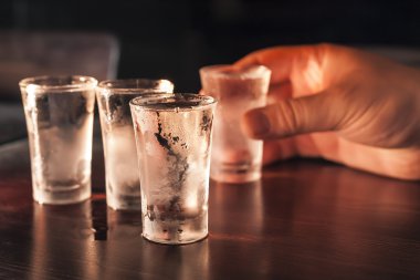 Shot glasses of vodka in hand.