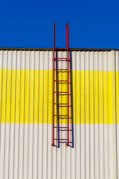 Red ladder on a white-yellow wall. — Stock Photo, Image