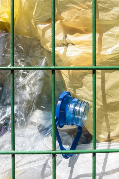 Cestino con bottiglie e sacchetti di plastica visibile . — Foto Stock
