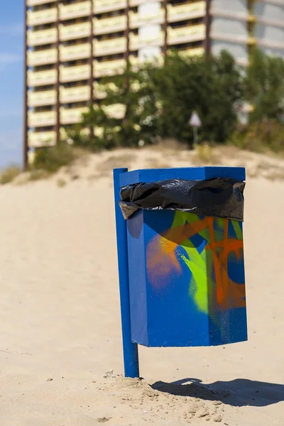 在海滩上涂鸦蓝色垃圾篮. — 图库照片