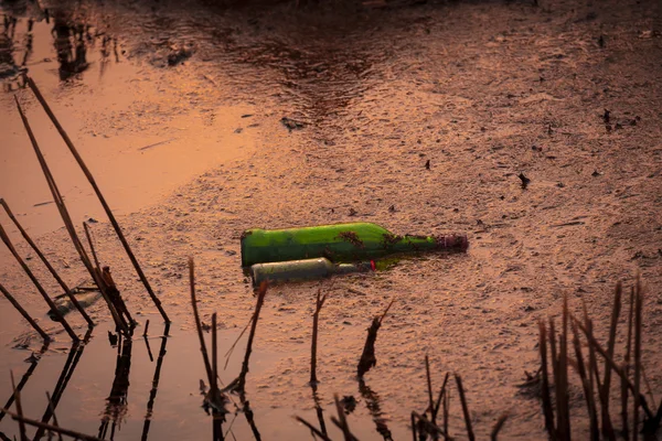 Grüne Flasche liegt im Teich. — Stockfoto