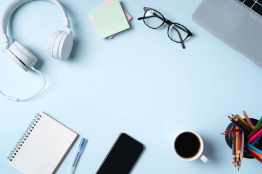 Çevrimiçi öğrenim tasarımı. Bilgisayarlı, kulaklıklı ve mavi masa arkaplanlı öğrenci tablosunun üst görünümü.