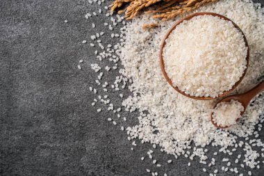 Siyah masa arka planında kulağı olan bir kasede beyaz çiğ pirinç..