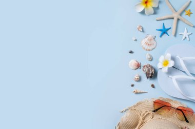 Yaz sahili tasarım konsepti. Deniz kabukları, şapka, mavi arka planda terlik ile tatil seyahatinin en üst görüntüsü.