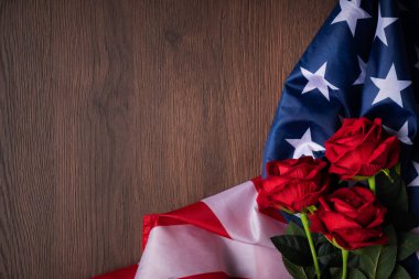 ABD kavramı. Bağımsızlık Günü ya da Anma Günü. Ulusal bayrak ve kırmızı gül koyu ahşap masa zemininde.