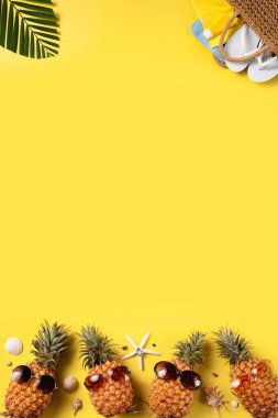 Yaz meyvesi tasarımı konsepti. Deniz kabukları, ananas ve sarı arka planda palmiye yaprakları olan tatil gezilerinin en iyi manzarası..