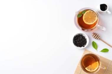 Beyaz masa arkasında sarı limon ve nane yaprağı olan ballı siyah çay konseptini tasarla.