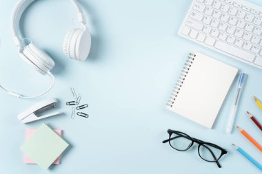 Çevrimiçi öğrenim tasarımı. Bilgisayarlı, kulaklıklı ve mavi masa arkaplanlı öğrenci tablosunun üst görünümü.