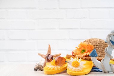 Yaz sahili tasarım konsepti. Tatil seyahatini kabuk, şapka, güneş gözlüğü ve beyaz masa arkaplanındaki terliklerle tamamlayın..