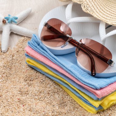 Yaz sahili tasarım konsepti. Tatil seyahatini kabuk, şapka, güneş gözlüğü ve beyaz masa arkaplanındaki terliklerle tamamlayın..