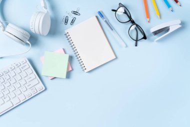 Çevrimiçi öğrenim tasarımı. Bilgisayarlı, kulaklıklı ve mavi masa arkaplanlı öğrenci tablosunun üst görünümü.