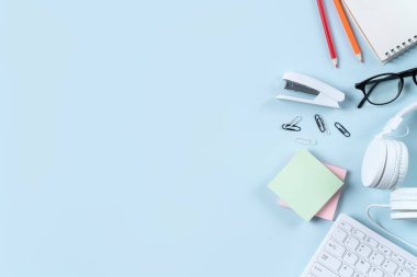 Çevrimiçi öğrenim tasarımı. Bilgisayarlı, kulaklıklı ve mavi masa arkaplanlı öğrenci tablosunun üst görünümü.