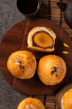 Ay pastası sarısı pastası, sonbahar ortası bayramı için ay çöreği koyu gri masa arkasında tatil.