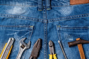 Mavi kot pantolon arka planında çalışma araçlarıyla İşçi Bayramı 'nın üst görünüm tasarım kavramı.