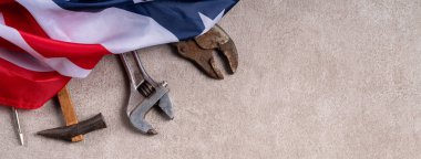 Gri masa arkasında çalışma araçları ile Amerikan İşçi Bayramı üst görünüm tasarım kavramı.