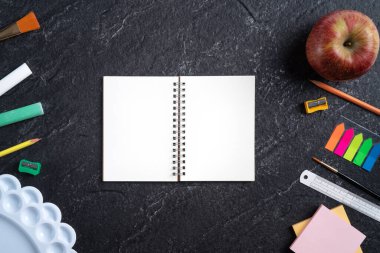 Okul öğrencilerinin tasarım konseptine geri dön, sayfa siyah masa arkaplanının üstündeki kırtasiyeye fotokopi alanı ile üst görünüm.