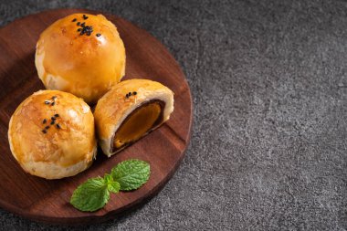 Ay pastası sarısı pastası, ay çöreği, Güz ortası festivali tatili için koyu gri masa arkasında.