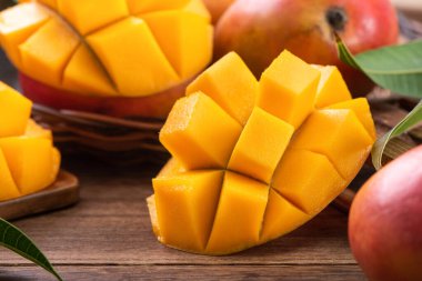 Mango. Taze olgun mango meyvelerini koyu ahşap masa zemininde yeşil yapraklarla kaplayın..