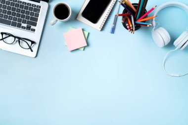 Çevrimiçi öğrenim tasarımı. Bilgisayarlı, kulaklıklı ve mavi masa arkaplanlı öğrenci tablosunun üst görünümü.