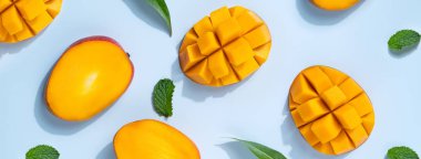 Mango tasarım konsepti. Mavi masa arkasında doğranmış taze mango meyvesi desenlerinin üst görüntüsü.