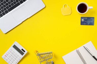Kredi kartı, not, hesap makinesi ve bilgisayar ile çevrimiçi alışveriş tasarımı kavramının üst görünümü ofis sarı masa arka planında izole edildi.