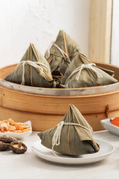 Zongzi. Rice dumpling for Chinese traditional Dragon Boat Festival (Duanwu Festival) on bright wooden table background with window.