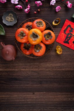 Çin 'in yeni yıl meyve tasarımı konsepti için ahşap masa arkasında yaprakları olan taze hurma hurmalarının üst görüntüsü..