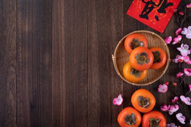 Çin 'in yeni yıl meyve tasarımı konsepti için ahşap masa arkasında yaprakları olan taze hurma hurmalarının üst görüntüsü..