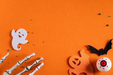 Turuncu kağıt masa zemininde yaratıcı Cadılar Bayramı konsepti dekorasyonunun en üst görüntüsü.