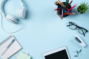 Çevrimiçi öğrenim tasarımı. Tabletli, kulaklıklı ve mavi masa arkaplanlı öğrenci tablosunun üst görünümü.