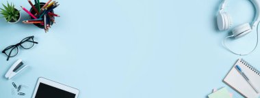 Çevrimiçi öğrenim tasarımı. Tabletli, kulaklıklı ve mavi masa arkaplanlı öğrenci tablosunun üst görünümü.