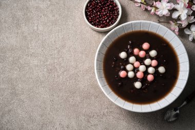 Kırmızı ve beyaz tangyuan 'ın (tang yuan, glutinous rice dumpling balls) en üst görüntüsü. Gri masa üzerinde tatlı kırmızı fasulye çorbası ile kış gündönümü festivali yemekleri için..