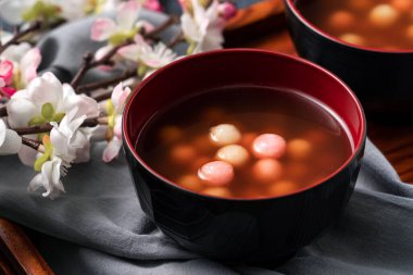 Kırmızı ve beyaz tangyuan 'a (tang yuan, glutinous rice dumpling balls), kış gündönümü festivali için mavi masa arkasındaki tatlı şurup çorbasına yakın durun..