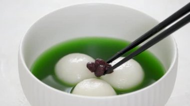 Matcha büyük tangyuan 'ı (tang yuan) tatlı kibrit çorbası ve kırmızı fasulye ezmesi ile beyaz masa arkasında festival yemeği için hazırlamaya yakın durun..