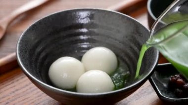 Matcha büyük tangyuan 'ı (tang yuan) tatlı kibrit çorbası ve kırmızı fasulye ezmesi ile beyaz masa arkasında festival yemeği için hazırlamaya yakın durun..
