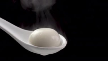 Siyah arka planda beyaz kaşıkta taze ve sıcak Tangyuan pirinç köftesi. Kış gündönümü için yiyecek, yakın çekim..