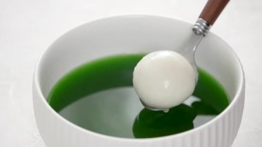 Matcha büyük tangyuan 'ı (tang yuan) tatlı kibrit çorbası ve kırmızı fasulye ezmesi ile beyaz masa arkasında festival yemeği için hazırlamaya yakın durun..