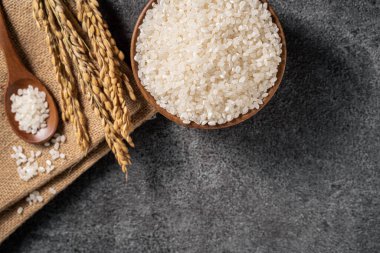 Siyah masa arka planında kulağı olan bir kasede beyaz çiğ pirinç..