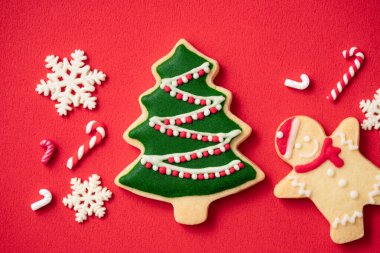 Kırmızı masa arkaplanındaki süslü Noel kurabiyelerinin fotokopi alanı, bayram kutlaması konsepti.