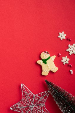Süslü Noel kurabiyelerinin üst görüntüsü kırmızı masa arkasında fotokopi alanı ve bayram kutlaması konseptiyle süslenmiş..