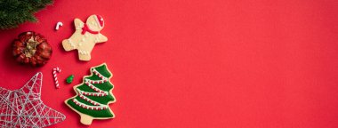 Süslü Noel kurabiyelerinin üst görüntüsü kırmızı masa arkasında fotokopi alanı ve bayram kutlaması konseptiyle süslenmiş..