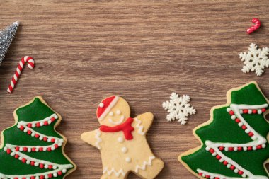 Süslü Noel kurabiyelerinin en üst görüntüsü ahşap masa arkasında fotokopi alanı ve tatil kutlaması konseptiyle süslenmiş..