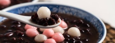 Kırmızı ve beyaz tangyuan 'a (tang yuan, glutinous rice dumpling balls) kışın gündönümü festivali için beyaz masa arkasındaki tatlı kırmızı fasulye çorbasıyla yakın çekim yapın..