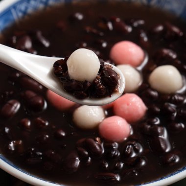 Kırmızı ve beyaz tangyuan 'a (tang yuan, glutinous rice dumpling balls) kışın gündönümü festivali için beyaz masa arkasındaki tatlı kırmızı fasulye çorbasıyla yakın çekim yapın..
