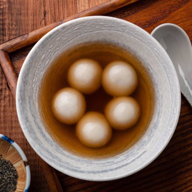 Büyük susam tangyuan 'ın (tang yuan, glutinous rice dumpling balls) en üst görüntüsü. Kış gündönümü festivali için ahşap masa arkasındaki tatlı şurup çorbası..