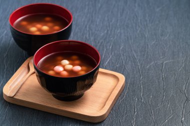 Kırmızı ve beyaz tangyuan 'a (tang yuan, glutinous rice dumpling balls), kış gündönümü festivali için mavi masa arkasındaki tatlı şurup çorbasına yakın durun..