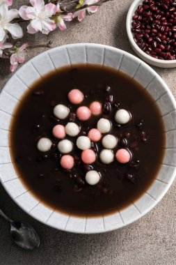Kırmızı ve beyaz tangyuan 'ın (tang yuan, glutinous rice dumpling balls) en üst görüntüsü. Gri masa üzerinde tatlı kırmızı fasulye çorbası ile kış gündönümü festivali yemekleri için..