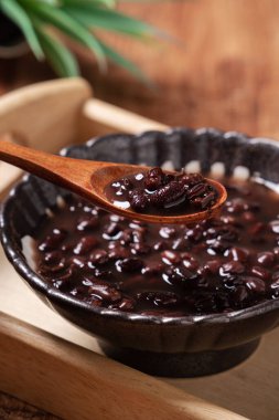 Azuki kırmızı fasulye çorbasını ahşap masa arkasında yemek için bir kaseye koy..