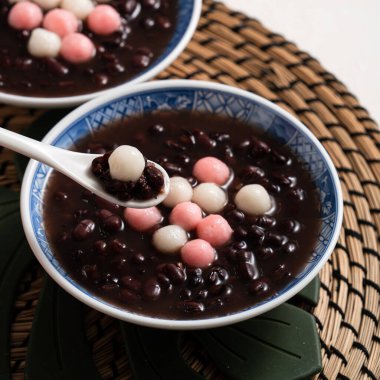 Kırmızı ve beyaz tangyuan 'a (tang yuan, glutinous rice dumpling balls) kışın gündönümü festivali için beyaz masa arkasındaki tatlı kırmızı fasulye çorbasıyla yakın çekim yapın..